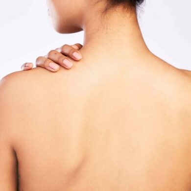 Be kind to your body. Rearview shot of a young woman posing with her hand on her shoulder