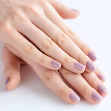 Closeup of hands of a young woman with pink manicure on nails against white background